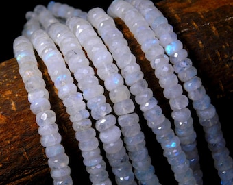 May include: Multiple strands of faceted, translucent white moonstone beads arranged in parallel lines. Each bead features a circular, disc-like shape with a polished finish, displaying subtle iridescent blue flashes when light hits the surface.