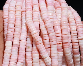 Pode incluir: Uma coleção de múltiplos fios de contas em forma de disco de cor rosa pálido. Cada conta apresenta uma borda lisa e arredondada e um perfil plano consistente, criando uma aparência uniforme em todo o conjunto de componentes de joalharia.