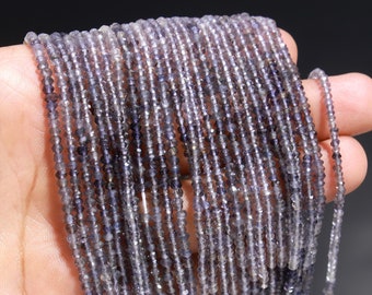 May include: A long strand of small, faceted, translucent purple iolite beads arranged in multiple parallel rows. Each bead features a polished, multi-sided cut that reflects light, creating a shimmering effect across the entire length of the gemstone string.