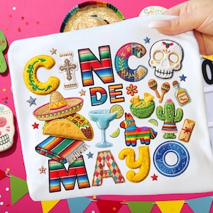 May include: White Cinco de Mayo themed design with embroidered images of a sombrero, taco, margarita, and a sugar skull. The design includes the text "CINCO DE MAYO" in colorful, textured lettering, along with other festive elements.