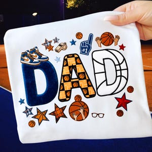 Puede incluir: Una taza de cerámica blanca con asa negra y el texto "But First, Coffee" en negrita negra. La taza se encuentra sobre un fondo neutro, resaltando su diseño sencillo.