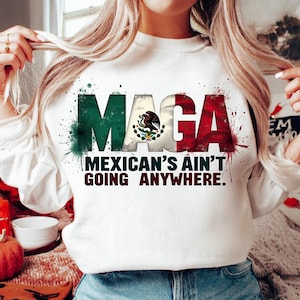 May include: White sweatshirt with the text "MAGA" in green and red, with the Mexican flag incorporated into the letters. The phrase "MEXICAN'S AIN'T GOING ANYWHERE" is printed below. The design includes green and red paint splatter.