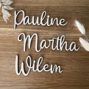 May include: Three wooden name signs with the names Pauline, Martha, and Willem written in cursive script.