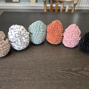 May include: Six crocheted beanies in various colors, including beige, white with black flecks, light blue, orange, pink, and black.