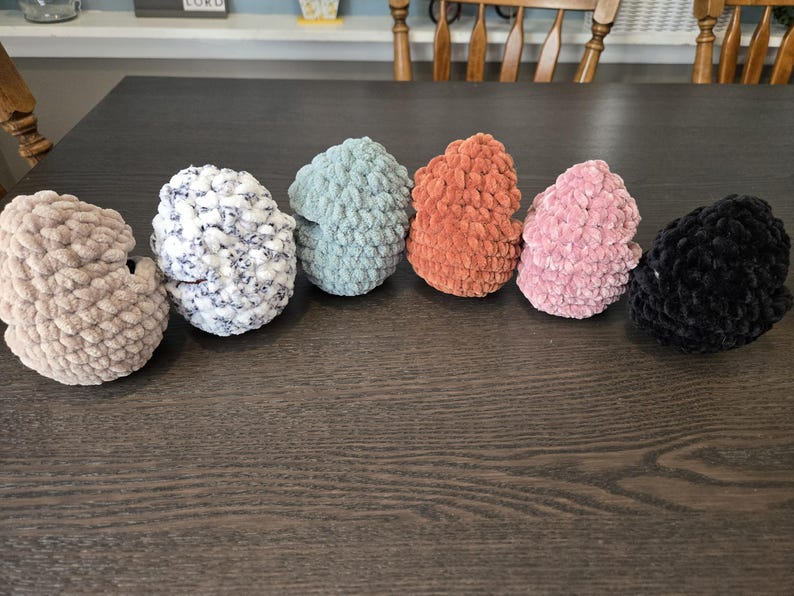 May include: Six crocheted beanies in various colors, including beige, white with black flecks, light blue, orange, pink, and black.