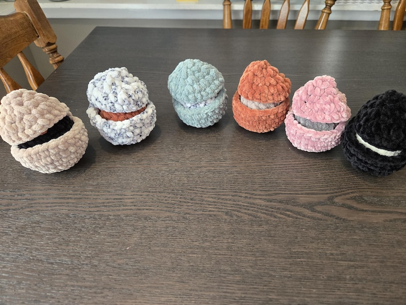 May include: Six crocheted, round, fabric containers with lids. The containers are in various colors, including beige, gray, blue, orange, pink, and black.