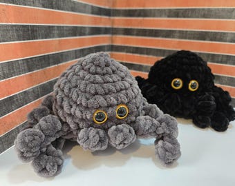 May include: Two crocheted octopus plushies with large, round, black eyes. One octopus is gray and the other is black.