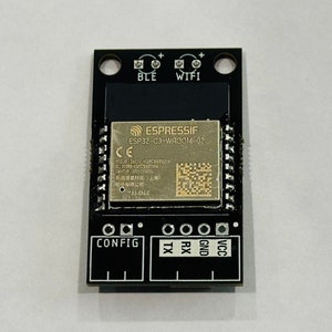 Pode incluir: Uma placa de circuito impresso preta com um chip ESP32-C3-WROOM-02 dourado. A placa tem etiquetas para BLE, WIFI, CONFIG, TX, RX, GND e VCC.