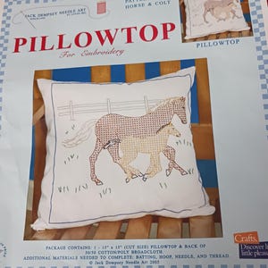 May include: A Pillowtop embroidery kit featuring a design of a horse and colt. The pillow has a white background with a stitched image of the two animals. The kit includes a 15" x 15" pillowtop and back.