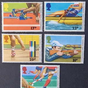 Könnte beinhalten: Vier farbige Briefmarken, die verschiedene Sportarten zeigen. Die Briefmarken stammen von den Commonwealth Games 1986 in Edinburgh, Schottland. Die abgebildeten Sportarten sind Leichtathletik, Rudern, Gewichtheben und Schießen. Die Briefmarken zeigen auch den Text "COMMONWEALTH GAMES EDINBURGH 1986" und den Preis jeder Briefmarke in Pence.