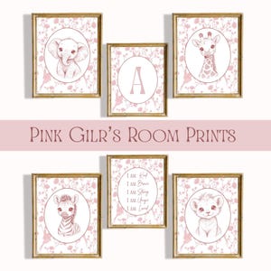 May include: Set of six framed pink nursery prints. Each print features a different design: an elephant, a giraffe, a zebra, a lion, the letter "A", and an inspirational quote. The prints are surrounded by a floral pattern and the text "PINK GIRL'S ROOM PRINTS".