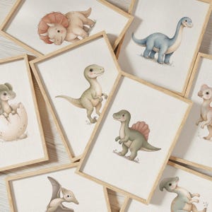 Puede incluir: Una colección de láminas de arte mural enmarcadas con ilustraciones en acuarela de varios dinosaurios, incluyendo un triceratops, un saurópodo de cuello largo, un raptor, un dinosaurio con cresta dorsal y un pterosaurio sobre fondo blanco.