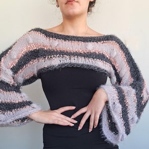 May include: A striped cropped sweater with long sleeves and a fuzzy texture in shades of pink and gray.