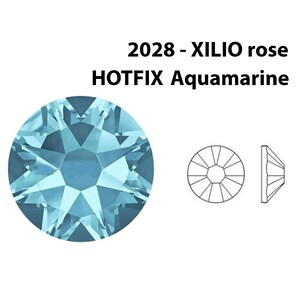 May include: A light blue, round, faceted rhinestone with a star-shaped design. The rhinestone is labeled "2028 - XILIO rose HOTFIX Aquamarine".