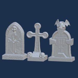 Op de afbeelding: Drie Halloween-graven, een met een kruis, een met een schedel en vleugels en een met een schedel en een spinnenweb. De graven zijn allemaal gemaakt van wit plastic en hebben de inscripties "R.I.P." en "Trick or Treat".