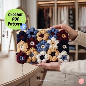 Peut inclure: Pochette au crochet faite à la main avec un motif floral dans les tons de bleu, crème et bordeaux. Le sac rectangulaire est orné d'une chaîne argentée. Le texte "Crochet PDF Pattern" est visible.
