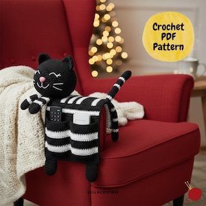 May include: A black and white crochet cat-shaped organizer with pockets, draped over a red armchair. The cat has a smiling face and striped arms and tail. The organizer has two pockets holding a remote and a device. The text "Crochet PDF Pattern" is in a yellow circle.