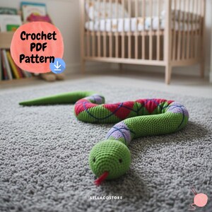 May include: A crocheted snake toy with a green head and body, featuring a red tongue. The body has a green, red, and purple argyle pattern. The text "Crochet PDF Pattern" is in the upper left corner. The toy is on a grey carpet.