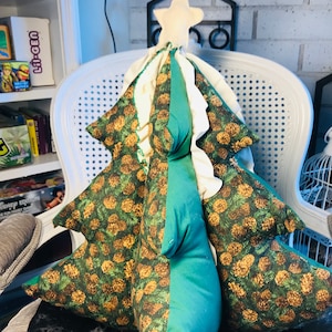 May include: A green and white Christmas tree pillow with a brown pine cone pattern. The pillow is shaped like a Christmas tree and has a white star on top.