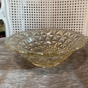 May include: A clear glass bowl with a scalloped edge and a diamond pattern. The bowl is slightly yellowed with age.