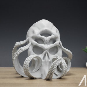 May include: A white 3D printed sculpture of a skull with tentacles. The skull has a single eye and a detailed, textured surface. The tentacles are curled around the skull and have a smooth, rounded texture.