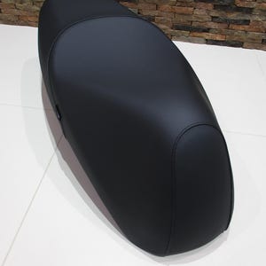 May include: A black motorcycle seat with a smooth, leather-like finish. The seat has an oval shape and appears to be new. The word "SEMINOLE" is printed in a stylized font at the bottom of the image.