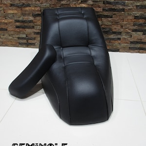 May include: Black leather motorcycle seat with a backrest. The seat has a stitched design and the word "SEMINOLE" is printed on the floor.