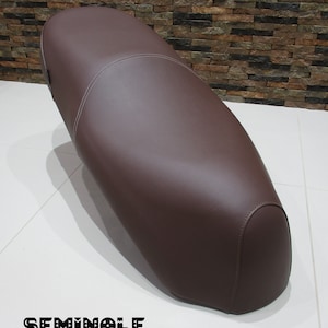 May include: A brown leather motorcycle seat with a stitched seam down the centre.