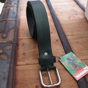 Puede incluir: Un cinturón de cuero verde oscuro con una hebilla plateada. El cinturón está enrollado y tiene una pequeña etiqueta adjunta que dice "DEITS SEHNKOL".