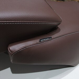 May include: Brown leather motorcycle seat with white stitching and the word "Seminole" embossed on the side.