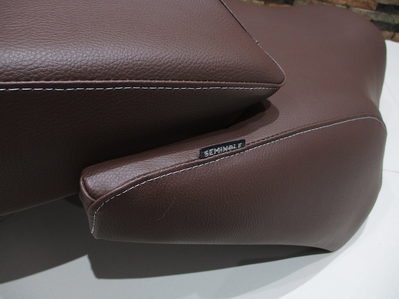 May include: Brown leather motorcycle seat with white stitching and the word "Seminole" embossed on the side.