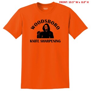 May include: Orange t-shirt with a black graphic of a ghost holding a knife and the text "Woodsboro Knife Sharpening".