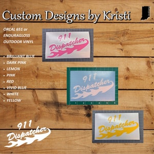May include: Three vinyl decals with the text "911 Dispatcher" in a stylized font with flames. The decals are shown on a wood background. The decals are available in pink, white, and yellow.