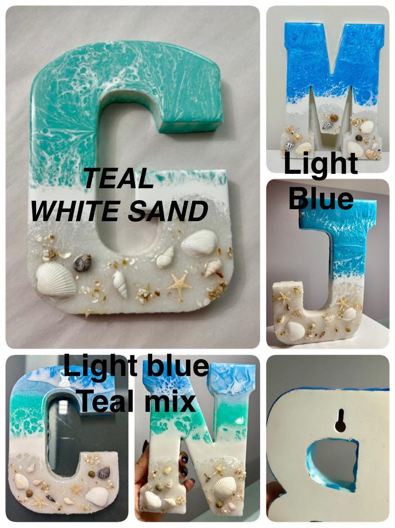 May include: Resin letters in various shades of blue and white, resembling ocean waves and sand. Each letter is adorned with seashells and starfish. The letters include the letters G, M, J, N, and R. The text "TEAL WHITE SAND" is visible.