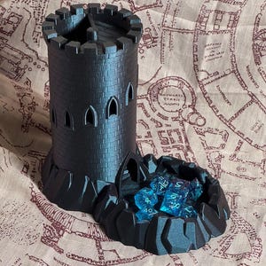 Könnte beinhalten: Ein schwarzer 3D-gedruckter Turm mit einem Würfeltablett. Der Turm hat ein Zinnen-Dach und Fenster. Das Tablett ist mit blauen Würfeln gefüllt.