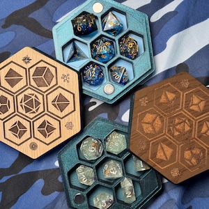 May include: A collection of hexagonal dice trays and wooden dice holders. The trays are teal, brown, and natural wood, each holding various polyhedral dice. The dice are blue, clear, and gold, with visible numbers. The wooden holders feature engraved geometric shapes.