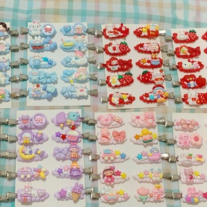 May include: Assortment of colorful hair clips with various cartoon characters and designs. The clips are attached to silver metal alligator clips. The designs include clouds, stars, hearts, and bows.