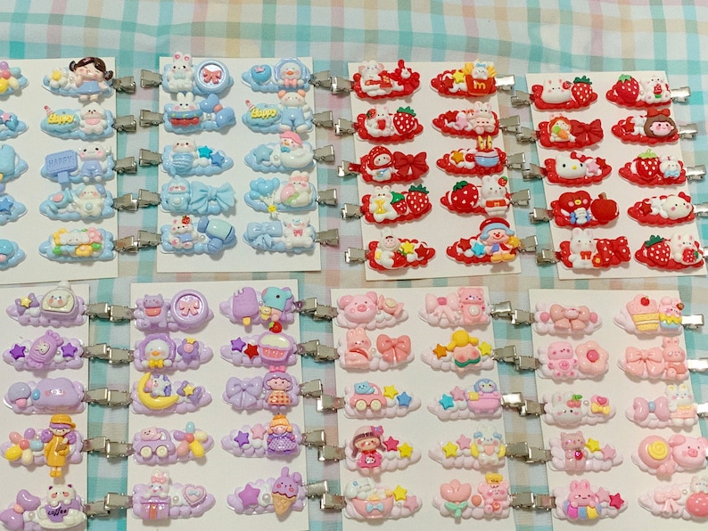 May include: Assortment of colorful hair clips with various cartoon characters and designs. The clips are attached to silver metal alligator clips. The designs include clouds, stars, hearts, and bows.