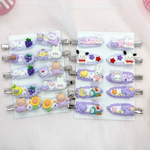 May include: Set of 18 purple and white hair clips with various cartoon animal and character designs. The clips are on two white cards.