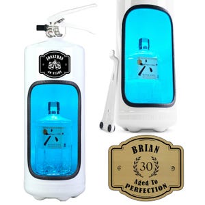 Pode incluir: Um extintor de incêndio branco reaproveitado como armário de bebidas com uma janela interior azul brilhante exibindo uma garrafa de Roku Gin. O exterior apresenta um rótulo preto escrito Jonathan 40 Years. Uma placa dourada separada diz Brian 30 Aged To Perfection.
