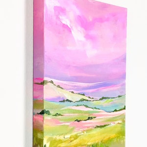 Puede incluir: Pintura abstracta de un paisaje con colinas onduladas y un cielo rosa. Las colinas est&aacute;n pintadas en tonos de verde, amarillo y rosa. El cielo es de un rosa vibrante con toques de morado y blanco.