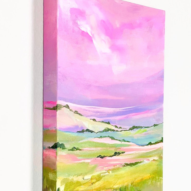 Puede incluir: Pintura abstracta de un paisaje con colinas onduladas y un cielo rosa. Las colinas est&aacute;n pintadas en tonos de verde, amarillo y rosa. El cielo es de un rosa vibrante con toques de morado y blanco.