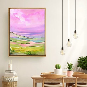 Puede incluir: Pintura abstracta de paisaje con un cielo rosa y morado, colinas verdes y un marco de madera.