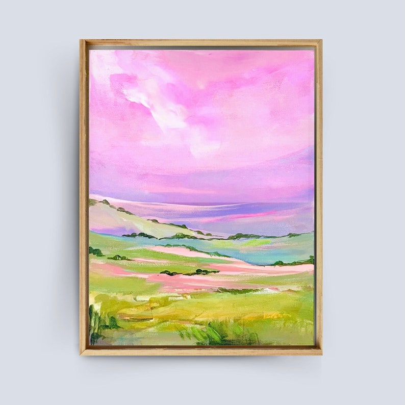 Puede incluir: Pintura abstracta de paisaje con un cielo rosa y morado y colinas verdes. La pintura est&aacute; enmarcada en un marco de madera claro.