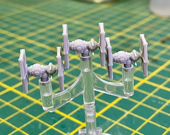 Op de afbeelding: Vier grijze TIE-fighter model kits zijn gemonteerd op een transparante kunststof standaard. De TIE-fighters staan in verschillende posities, sommige met de voorkant naar voren en andere met de zijkant naar voren. De standaard heeft een Y-vormige basis en drie verticale steunen.