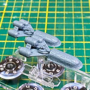 May include: Two grey plastic miniature spaceships with detailed designs. The spaceships are on clear plastic stands.