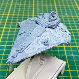 May include: A gray plastic model of a spaceship with a detailed design and a small engine on the top.