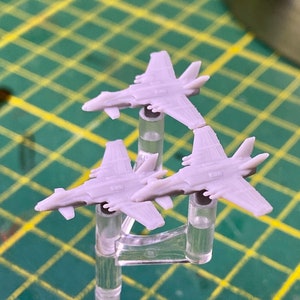 Puede incluir: Tres aviones modelo de pl&aacute;stico gris en soportes de pl&aacute;stico transparente. Los aviones est&aacute;n en formaci&oacute;n con las alas de los aviones apuntando hacia el espectador.