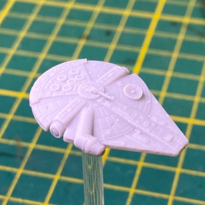 Peut inclure: Un modèle en plastique blanc du vaisseau spatial Millennium Falcon de Star Wars. Le modèle est détaillé avec les caractéristiques de conception emblématiques du vaisseau, y compris le cockpit, le moteur et les ailes.