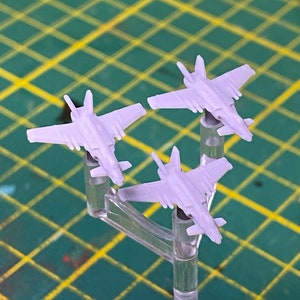 May include: Three miniature grey plastic model airplanes on a clear plastic stand. The airplanes are arranged in a triangular formation.
